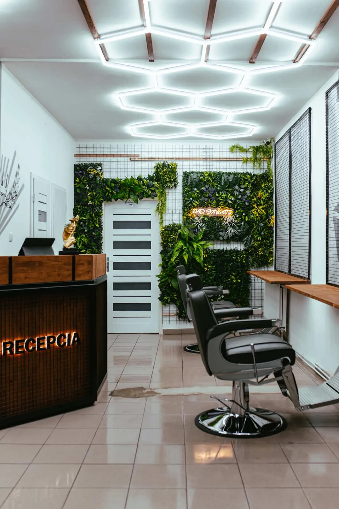 Recepcia holičstva East Barber so zeleňou a neónovým logom